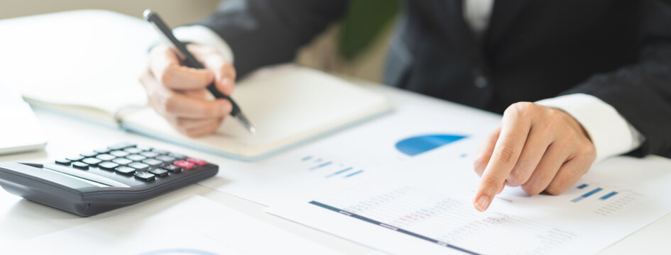 Close up of business woman accountant hand pointing at financial chart document and holding pen, analyzing corporate data report or budget planning for tax audit at office.