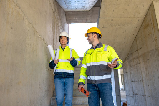 Female and male engineers discussing project while walking downstairs
