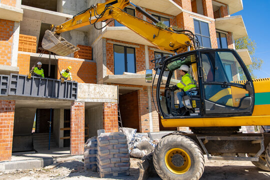 Female operator controlling excavator while workers position panel