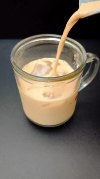 Authentic Indonesian Kopi Susu or instant coffee. Rich, creamy milk coffee in a transparent glass. 