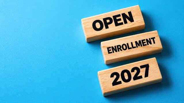 Open enrollment 2027 wooden blocks on blue background for corporate human resources usage.