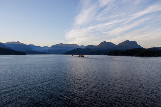 Tugboat and barges off the coast of BC  with mountains in the background at golden hour