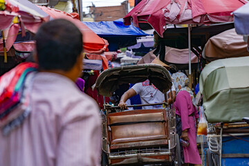 The situation of one corner in the traditional market with tarpaulin umbrellas and rickshaws and vendors' stands and rickshaw transport equipment © Oryzapratama