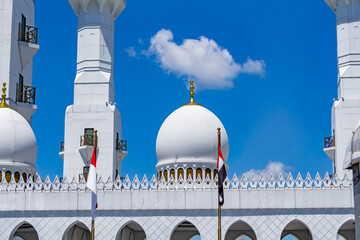 White dome of the mosque with flag on the foreground and blue sky on the background  © Oryzapratama