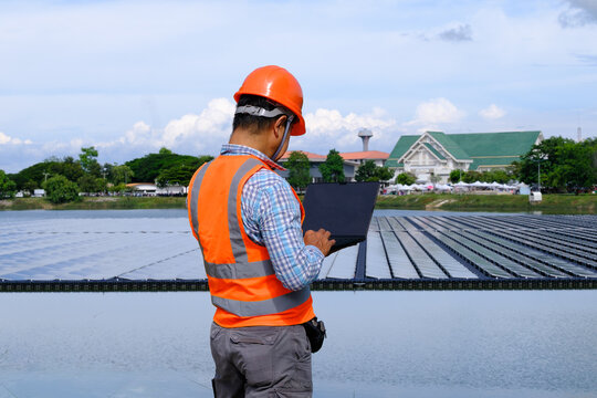 Worker in Safety Gear Inspects Solar Panels at Renewable Energy Project