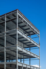 Obraz premium Multi story structural steel frame building under construction against a clear blue sky