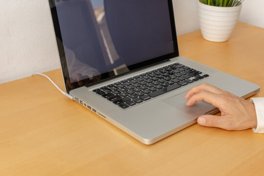 Hands using laptop trackpad on wooden desk