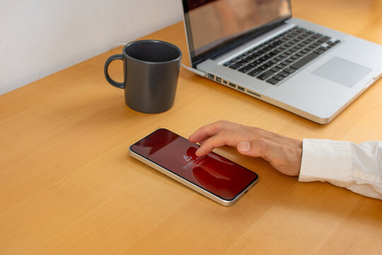 Man touching smartphone with security alert beside laptop