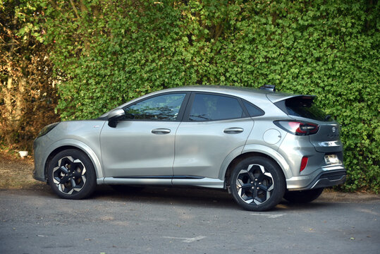 St-Amand Montrond - France - 15 September 2026 - Side view of a silver Ford Puma compact SUV parked along a roadside in front of a dense green hedge, featuring modern styling and distinctive alloy whe