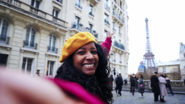 A joyful Black woman reaches toward the camera, smiles and walks with her partner along a Paris street near the Eiffel Tower.