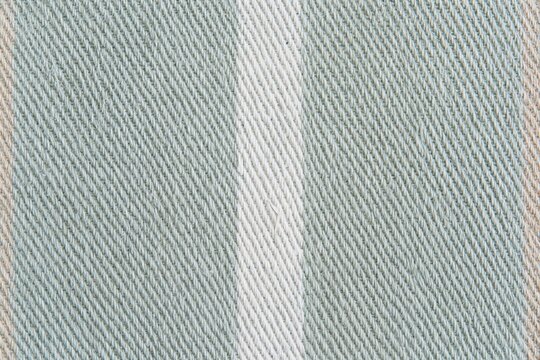 Cotton twill fabric with a fine diagonal weave and a pale sage green tone, featuring tactile ribbing for apparel and packaging backgrounds