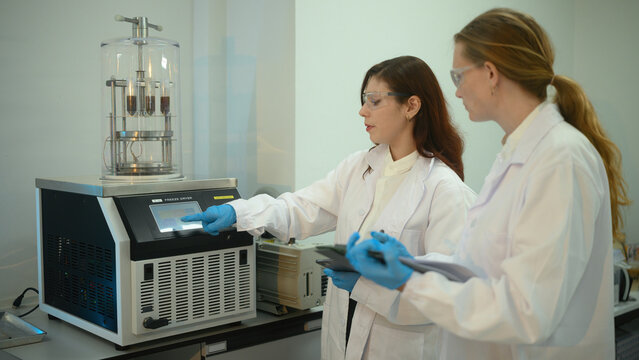 Caucasian Female Scientists Operating Freeze Dryer Machine in Modern Research Laboratory