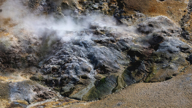 Steam billows from a fumarole vent among dark volcanic rocks at Kerlingarfjoll, Iceland, surrounded by colorful mineral crust.