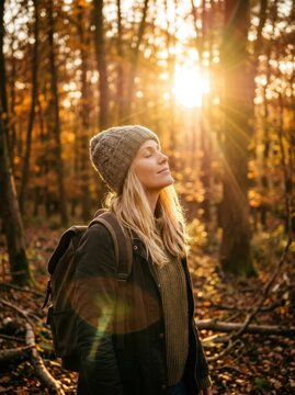 Young Woman Enjoying Peaceful Moment in Autumn Forest at Sunset with Golden Sunlight and Fall Foliage