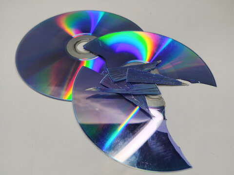 Broken and smashed compact discs with sharp shards on a white background
