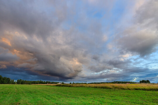 Green grassy field under dramatic storm clouds