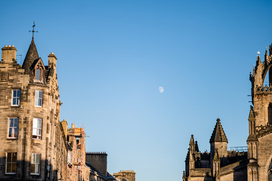 Edinburgh stone architecture beneath moon in clear blue sky