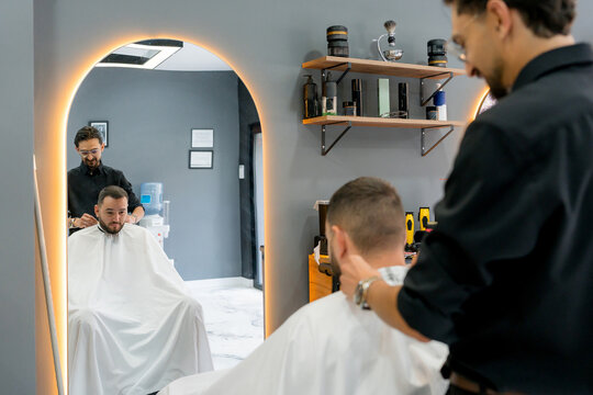 Professional barber prepare male client for haircut in barbershop