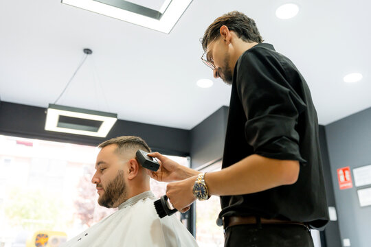 Barber use electric shaver for client haircut in barbershop