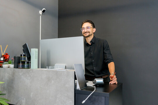 Barber at reception desk in modern barbershop interior