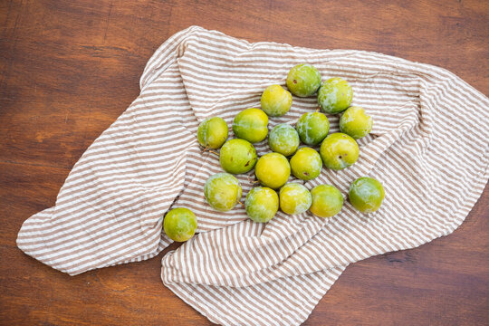 Fresh green plums on striped cloth for summer fruit season