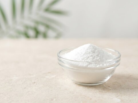 A small glass bowl filled with white baking soda powder on a light textured wooden surface. cbd isolate powder