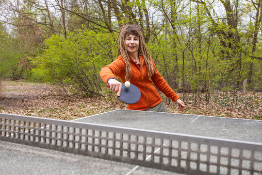 Woman play table tennis outdoors in a leafy park