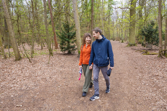 Couple walk together on woodland trail in early spring