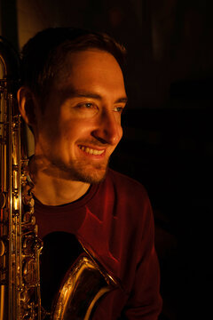 Smiling man with saxophone in warm dramatic light