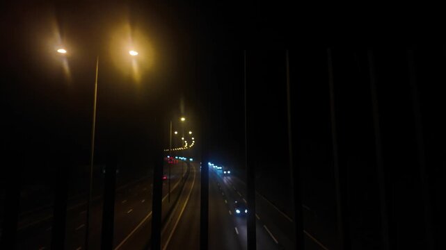 Night Highway Traffic View Looking Through Footbridge Fence on Motorway