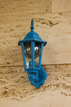 Vintage blue wall lantern mounted on beige travertine stone wall