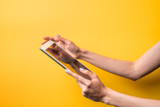 Woman hands hold tablet against yellow background