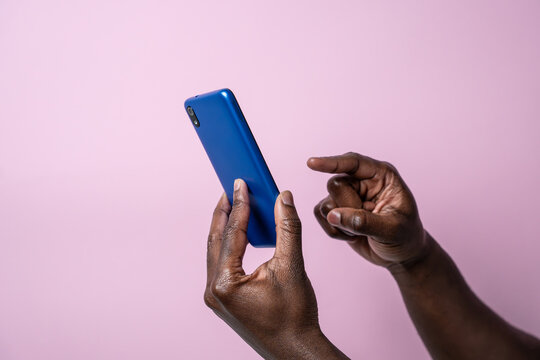 Black man hands hold blue smartphone against pink background