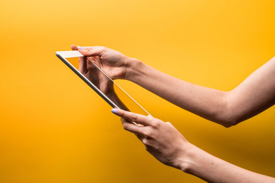 Woman hands hold tablet against yellow background