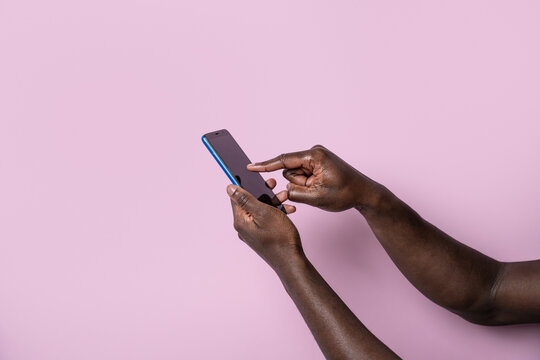 Black man hands use smartphone against pink background