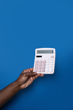 Black man hand holding calculator on blue background