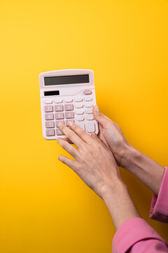 Woman hands use calculator on yellow background