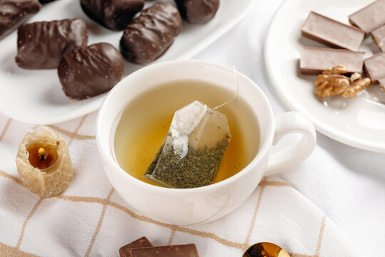 Assorted tea bags and chocolate sweets on white cloth