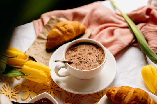 Cozy coffee and croissant breakfast with yellow tulips