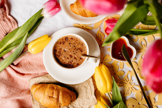 Spring breakfast with coffee, croissant and colorful tulips