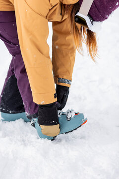 Woman fasten snowboard binding on snowy slope in Japan