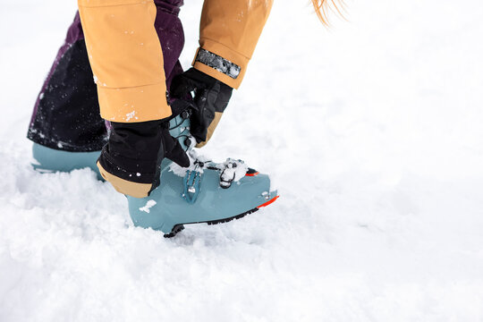 Person fastening ski boot in snow in Japan