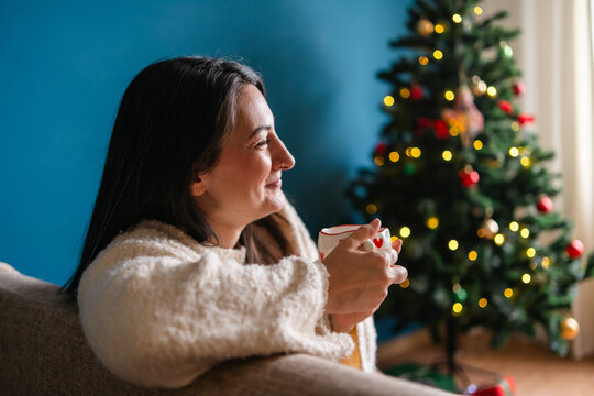 Woman enjoy coffee beside Christmas tree at home