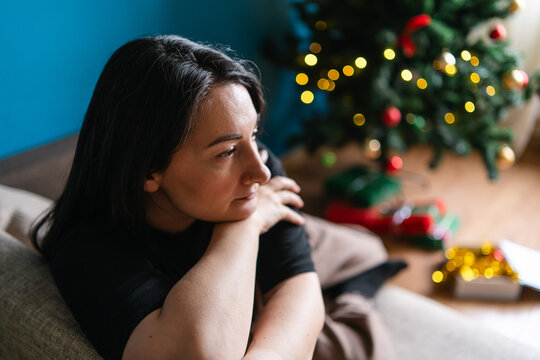 Lonely woman at home beside Christmas tree