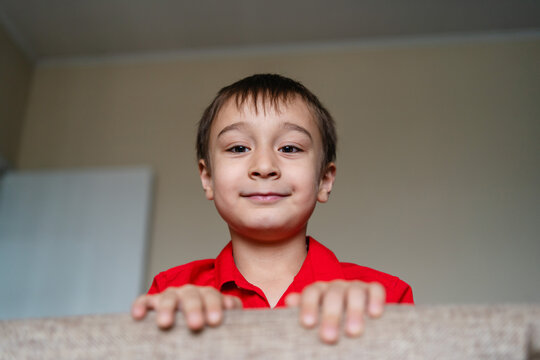 Smiling boy peek over sofa at home during Christmas