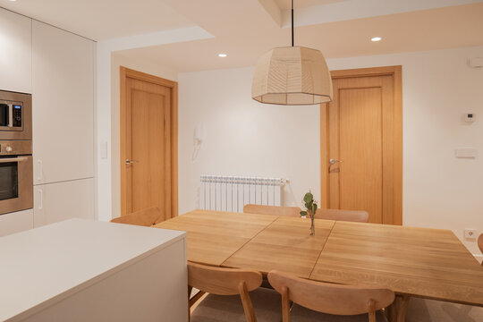 Modern apartment dining area with wood table and kitchen