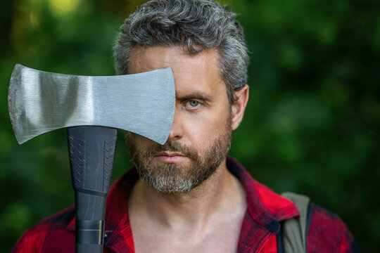 Lumberjack outdoor portrait. Brutal lumberjack. Brutality and masculinity. Hispanic lumberjack man face with axe. Lumberjack axe. Man with logging axe. Masculine brutal man portrait