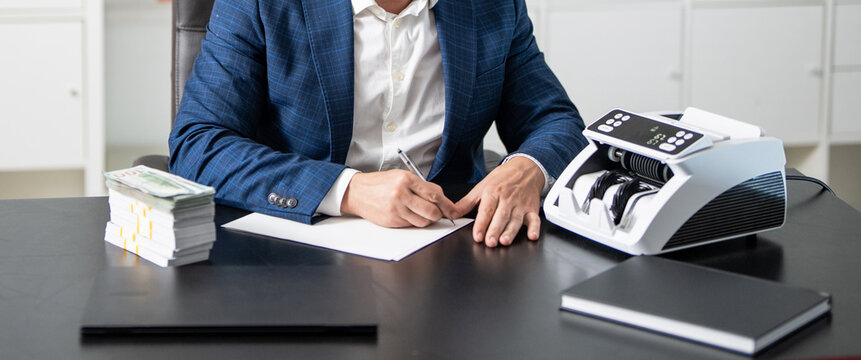 Man making notes at money counter. Economic wealth and value investing. Finance and business. Bank officer noting amount of dollar. Currency exchange. Businessman use bill counter, economy