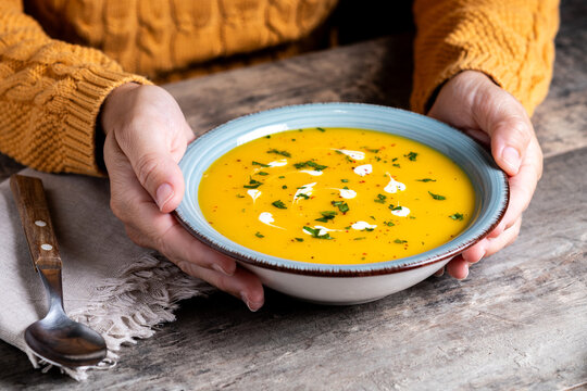 Creamy pumpkin soup with herb garnish on rustic table