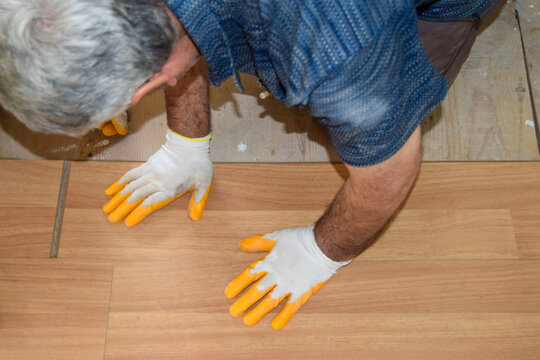 Craftsman install wood flooring with protective work gloves
